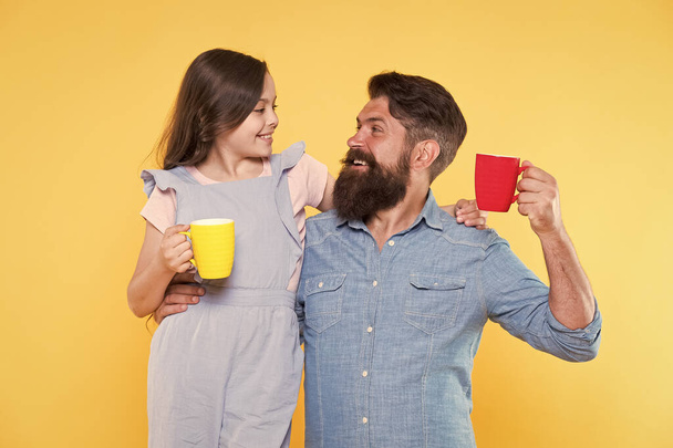 Bearded man and happy girl holding mugs. Father and daughter hot drink. Drink water. Drink fresh juice. Breakfast concept. Good morning. Having coffee together. Healthy lifestyle. Family drinking tea - Photo, image