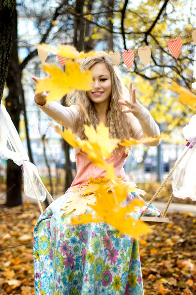 Щаслива дівчина кидає барвисте осіннє листя
 - Фото, зображення