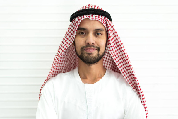 Portrait of happy smiling handsome middle eastern arab man in traditional clothing standing on white wall background - Foto, imagen