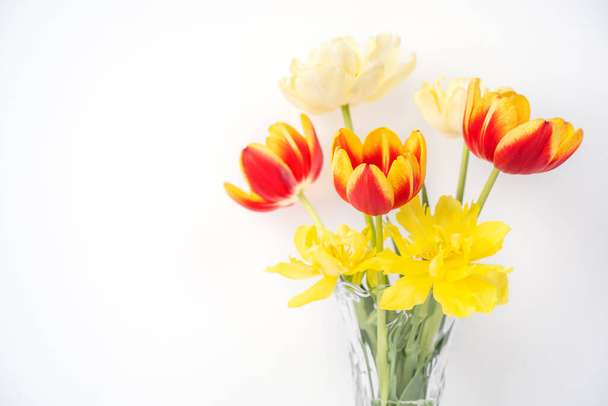 Kwiat tulipanów w szklanym wazonie z ramą na białym drewnianym tle stołu na czystej ścianie w domu, zbliżenie, koncepcja wystroju Dzień Matki. - Zdjęcie, obraz