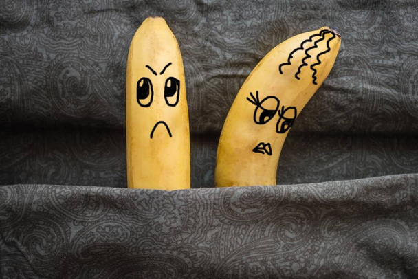 Conjoints dans un lit familial, ils s'en veulent. Métaphore, deux bananes - mari et femme. Fond sombre, lumière du jour. L'image est faite par l'auteur
. - Photo, image