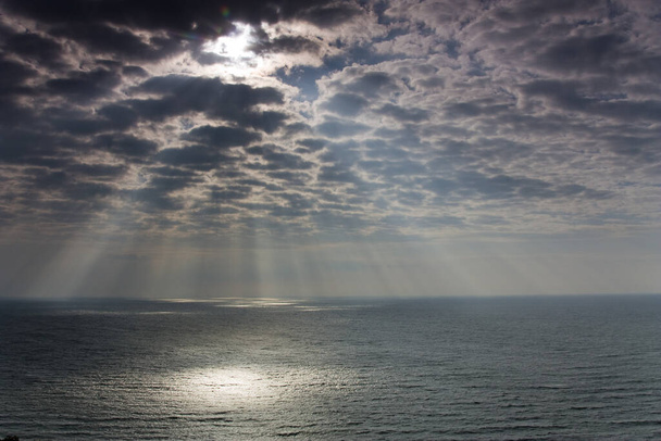 Itämeri kesällä aurinko taustavalossa ja tummissa pilvissä, Itämeri kesällä aurinko taustavalossa ja heijastuksia, auringonlasku valaisee oksat ja kivet merivedessä
 - Valokuva, kuva