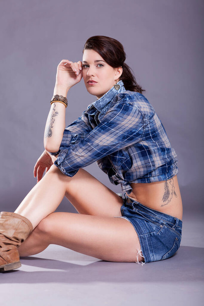 Young attractive woman in Western fashion with short pants carded shirt and dark hair - 写真・画像