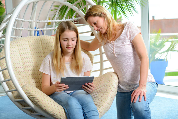 blonde mother and her daughter using tablet computer together - Zdjęcie, obraz