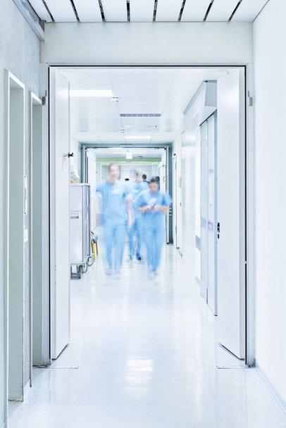 Flur mit offener Tür zur Intensivstation im Krankenhaus mit verschwommenen Ärzten aus dem Operationssaal - Foto, Bild