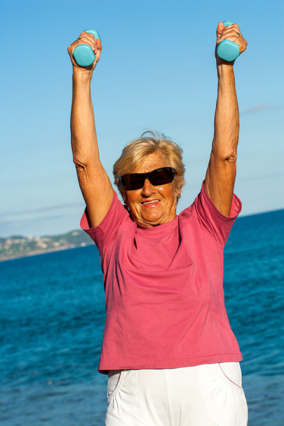 Senior woman lifting weights outdoors. - Foto, Bild