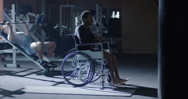 Wheelchair man sitting while others working out - Video, Çekim