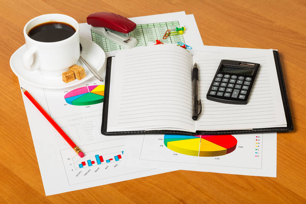 Cuaderno, calculadora, taza de café y suministros de oficina en el fondo del escritorio
. - Foto, Imagen