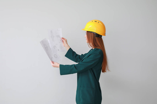Female engineer with drawings on light background - Фото, изображение