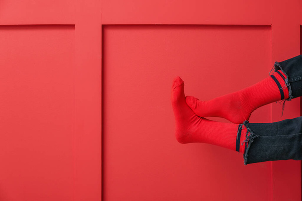 Πόδια νεαρής γυναίκας με κάλτσες και τζιν σε φόντο χρώματος - Φωτογραφία, εικόνα