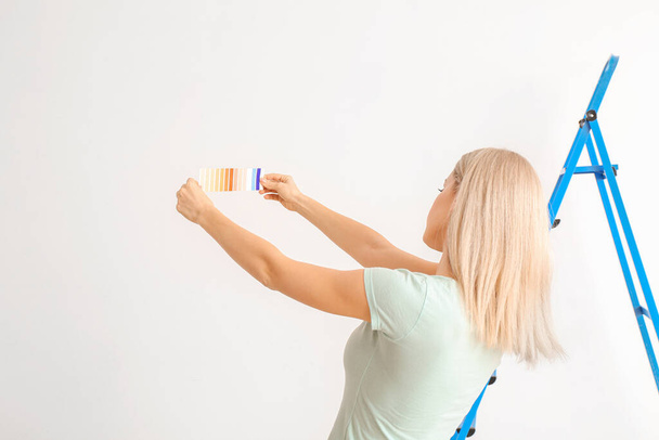 Jovem mulher escolhendo a cor da parede no fundo branco
 - Foto, Imagem