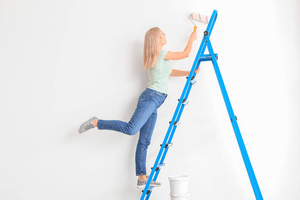 Young woman painting wall at home - Фото, изображение
