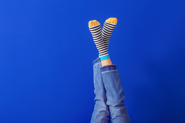 Πόδια της νεαρής γυναίκας σε ριγέ κάλτσες στο φόντο χρώμα - Φωτογραφία, εικόνα