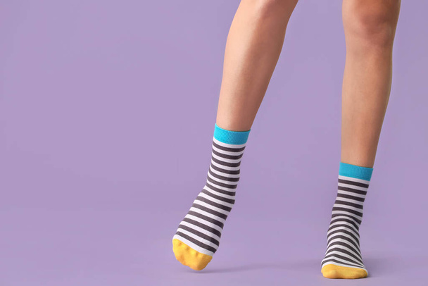 Beine der jungen Frau in gestreiften Socken auf farbigem Hintergrund - Foto, Bild