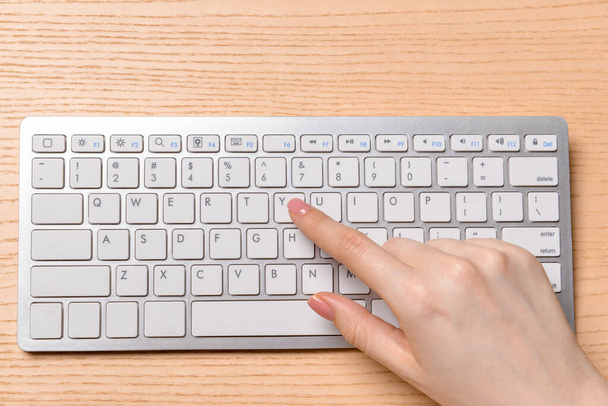 Female hand with computer keyboard on wooden background - 写真・画像