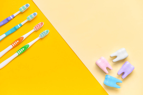 Зубні щітки та пластикові зуби на кольоровому фоні
 - Фото, зображення