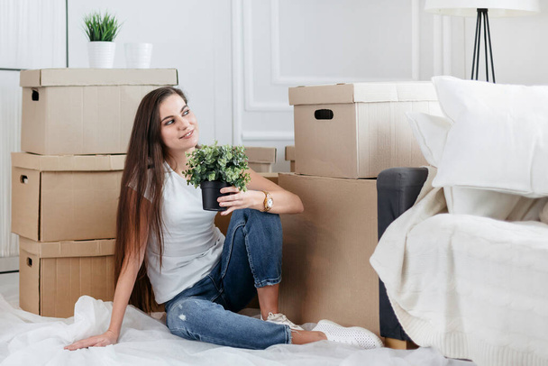 young woman dreams of sitting on the floor in a new apartment - Fotografie, Obrázek