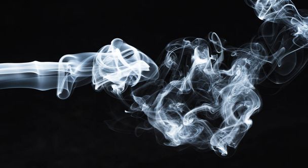 Background image of a wisp of smoke on a dark background. The texture of the flowing smoke. Frozen smoke on a dark background. Graphic resources dark backdrop. Texura of white clouds of fog. Curls of smoke frozen in motion. - Foto, Imagem