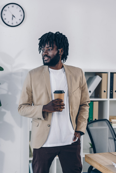 African american recruiter looking away with hand in pocket and paper cup of coffee in office - Fotoğraf, Görsel