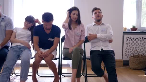 grupa osób z różnymi emocjami siedząca w rzędzie na krzesłach po spotkaniu terapeutycznym - Materiał filmowy, wideo