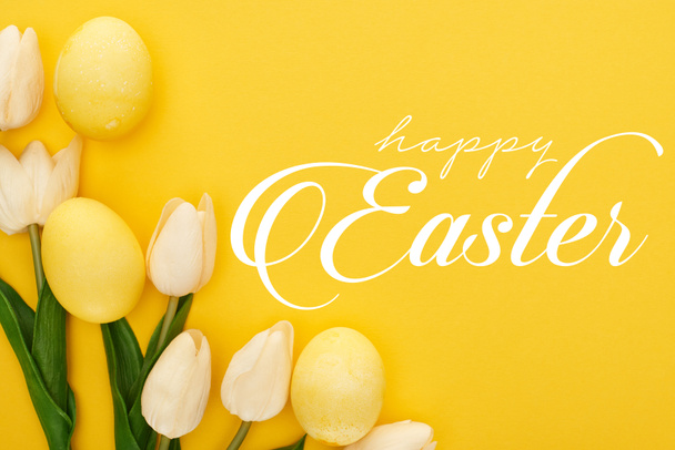 top view of tulips and painted Easter eggs on colorful yellow background with happy Easter illustration - Photo, Image