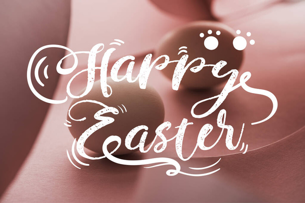 selective focus of chicken eggs in shadow in spiral paper pink swirls with happy Easter illustration - Fotó, kép