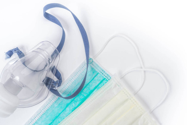 Tıbbi ultrasonik astım cihazı veya nebulizör oksijen maskesi ve beyaz arka planda hijyenik yüz maskeleri, kopyalama alanı - Fotoğraf, Görsel