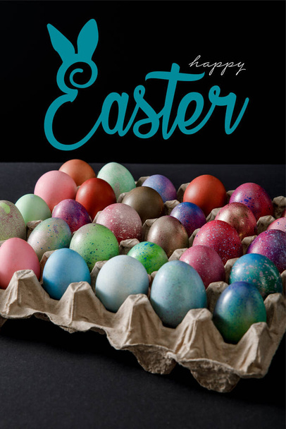 Siyah zemin üzerinde renkli Paskalya yumurtaları olan yumurta tepsisi ve mutlu Paskalya çizimleri. - Fotoğraf, Görsel