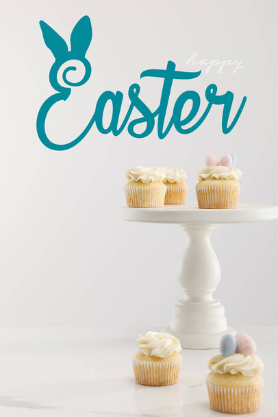 Selective focus of cupcakes on cake stand isolated on grey with happy Easter illustration - Foto, immagini