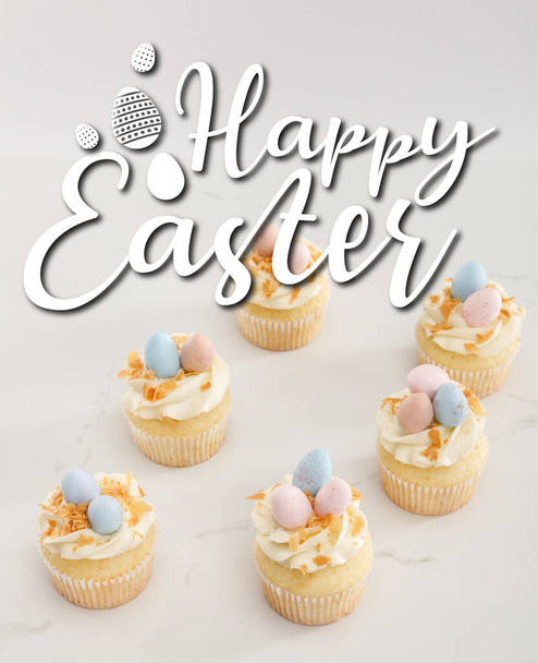 Delicious easter cupcakes with painted quail eggs on top on white background with happy Easter illustration - 写真・画像
