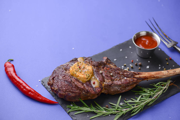 Grilled Medium rare barbecue Steak on bone with spices served on a rustic wooden board with sauce over blue background. - Foto, imagen