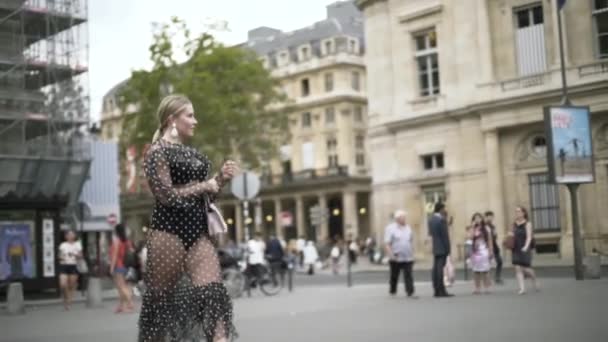 Mulher europeia elegante vestindo vestido sexy pontilhado preto e bolsa pequena branca, Paris, França. Acção. Loira plus size modelo andando na rua
. - Filmagem, Vídeo