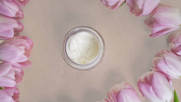 homemade organic cosmetic cream with frame of pink tulip flowers, skin care, remedy and beauty containers with white cream, flat lay - Photo, Image