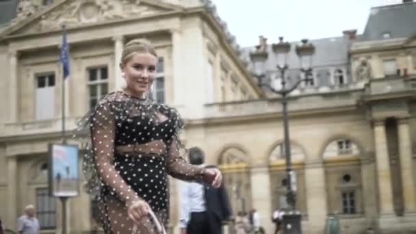 Elegante mujer europea con vestido sexy punteado negro y monedero pequeño blanco, París, Francia. Acción. Rubia modelo de tamaño grande caminando en la calle
. - Imágenes, Vídeo