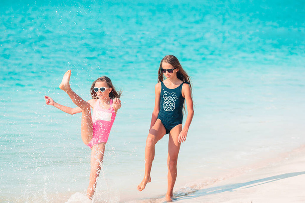 小さな幸せな面白い女の子は一緒に遊んで熱帯ビーチで多くの楽しみを持っています. - 写真・画像