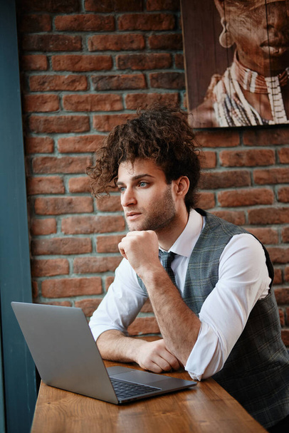 Attractive bearded young man working on laptop while sitting in - Photo, image