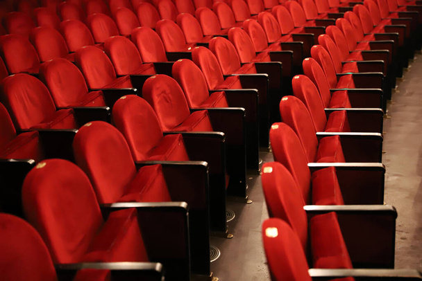 Des rangées classiques de sièges vides rougeâtres dans le théâtre. Hall sans visiteurs. Profondeur de champ faible
 - Photo, image