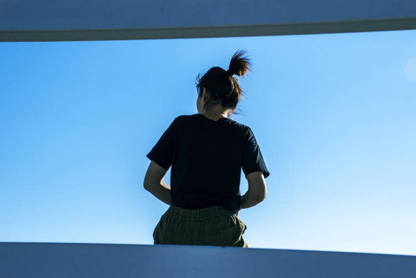 Κορίτσι κάθεται πίσω όψη, κατά τον ουρανό, θέση για κείμενο. - Φωτογραφία, εικόνα