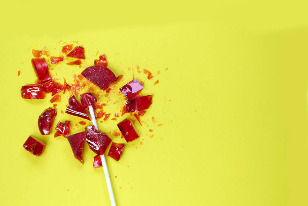 broken heart red lollipop sweet isolated on yellow background - Photo, Image