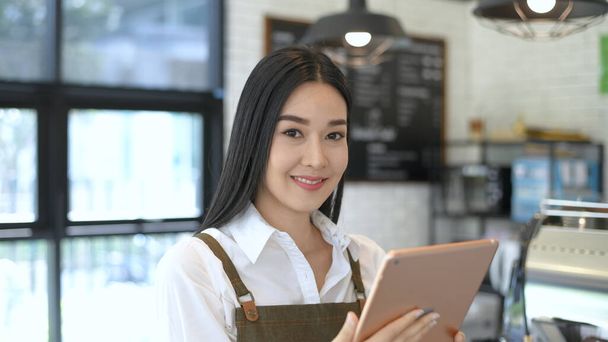 Coffee shop concept. The waitress is taking orders from customers with a tablet inside the coffee shop. 4k Resolution. - 写真・画像