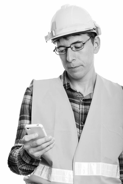 Studioaufnahme eines Bauarbeiters isoliert vor weißem Hintergrund in Schwarz-Weiß - Foto, Bild