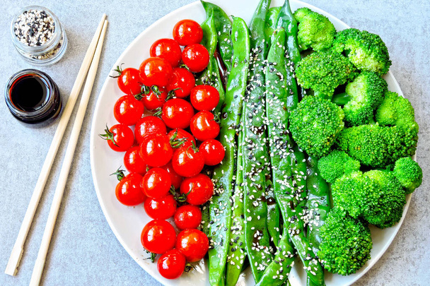 Aliments sains dans une assiette. Haricots verts, brocoli, tomates cerises. Salade utile de légumes verts avec tomates cerises cuites au four et graines de sésame. Produits pour la santé
. - Photo, image