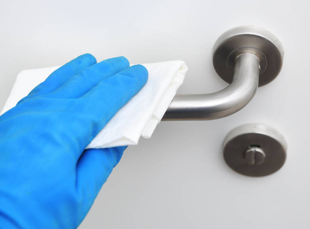 Disinfection in public places, the fight against the virus, coronavirus.Worker's hand wipes the door handles. A maid or housewife takes care of the house. Spring general or regular cleaning.  - Foto, Bild
