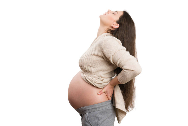 Zmęczona ciężarna kobieta odczuwa ból pleców wyizolowany na tle dziewięciu miesięcy ciąży - Zdjęcie, obraz