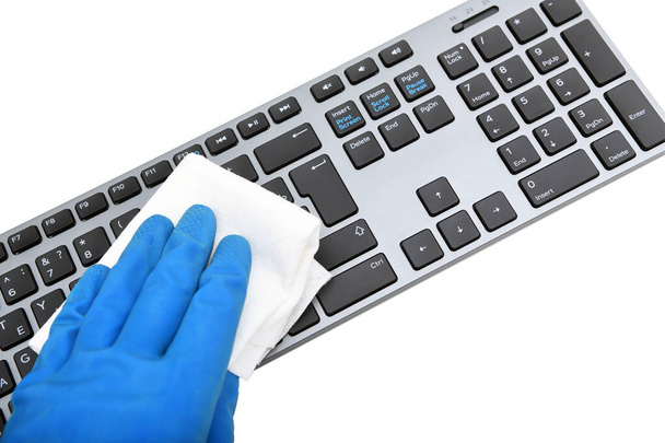 Worker's hand wipes dust and dirt on the keyboard. A maid or housewife takes care of the house. General, regular cleaning. The concept of a commercial cleaning company - Foto, afbeelding