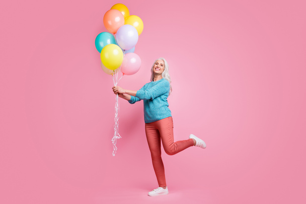 Full length photo of positive cheerful lovely pretty grandmother hold air helium baloons enjoy festive family occasion wear sweater pullover sneakers isolated pastel color background - Fotoğraf, Görsel