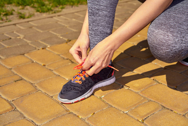 partial view of sportive woman tying shoelaces on her sneaker                 - Photo, image