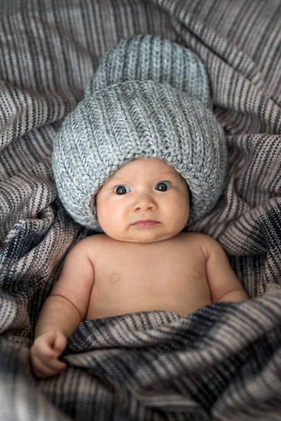 Portret van een pasgeboren baby met hoed en gewikkeld in bruine deken - Foto, afbeelding