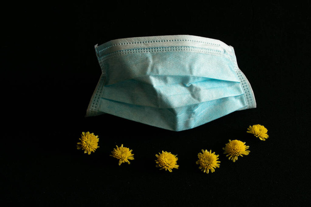 máscara médica y hermosos crisantemos amarillos sobre un fondo negro
 - Foto, imagen