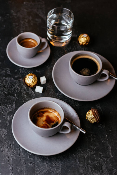 copos de café americano com doces de chocolate no fundo cinza
 - Foto, Imagem